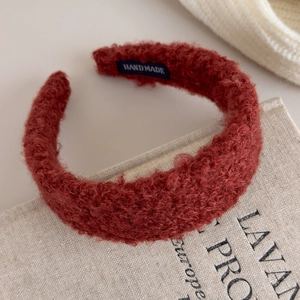 Detail of rust red plush headband with handmade label on soft textured fabric