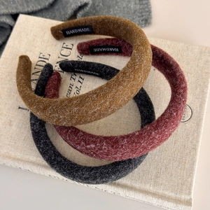 Close-up of three thick felt headbands in autumn colors with handmade labels on knit fabric