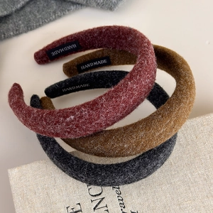 Three padded felt headbands in gray, red, and yellow on a vintage book backdrop