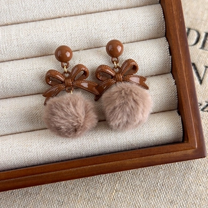 Détail de boucles d'oreilles vintage à nœud marron et pompon sur plateau à bijoux beige