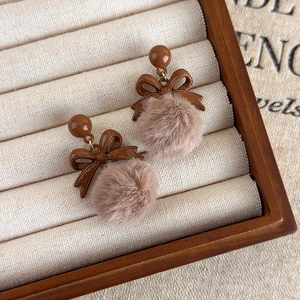 Vue détaillée des boucles d'oreilles à nœud vintage avec pompons en fourrure marron café