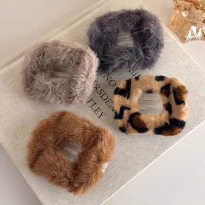 Lot de quatre pinces à cheveux en peluche grise, marron et léopard sur livre