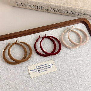 Three pairs of vintage flocking hoop earrings in brown, burgundy, and beige on wood tray