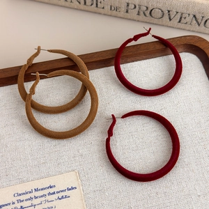 Close-up of velvet flocked hoop earrings in brown and wine red on a wooden tray