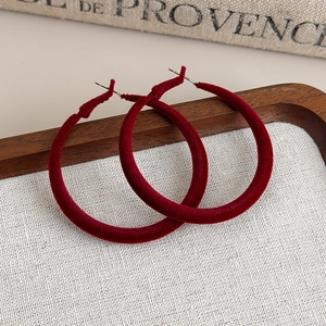 Macro shot of large burgundy flocked velvet hoop earrings on a vintage linen tray