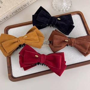 Close-up of velvet bow hair clips with gold 'Love' emblems in a vintage wooden tray