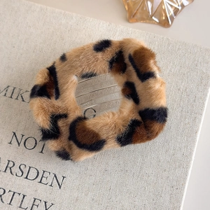 Détail d'une pince à cheveux en peluche à motif léopard sur un fond de livre ancien
