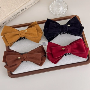 Detail of four velvet bow hair clips with gold metal labels on a vintage wooden tray