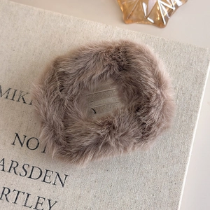 Gros plan sur une pince à cheveux en peluche marron café avec peigne interne transparent