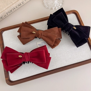 Close-up of suede bow hair clips in burgundy, brown and black with gold Love charms