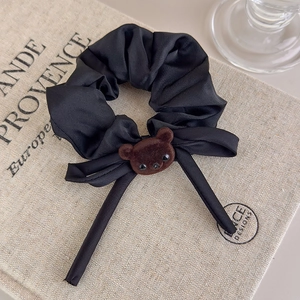 Detailed texture of black satin scrunchie with cute brown flocked bear and long ribbon