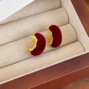 Primer plano de pendientes de terciopelo rojo vino vintage con borde dorado en caja