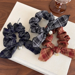 Close-up of vintage plaid bow scrunchies with metal charms on a white book
