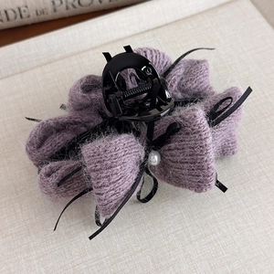 Dettaglio molletta per capelli con fiocco in maglia viola, perla e nastro di seta nero
