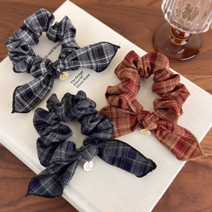 Detailed shot of three vintage plaid scrunchies with bow design and small gold charms