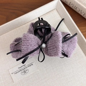 Dettaglio molletta per capelli a fiocco in maglia viola con nastri neri e perla bianca