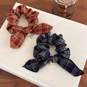Close-up of vintage plaid bow scrunchies with elegant gold charms on a textured book