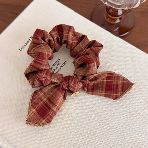 Close-up of red and yellow plaid scrunchie with bow knot and metal pendant