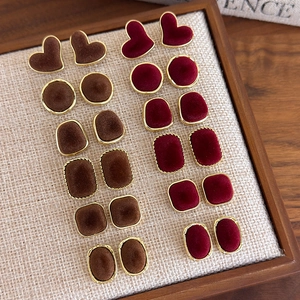 Detail of square and heart velvet stud earrings in brown and wine red with gold edges