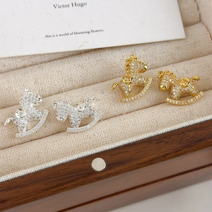 Detailed view of gold and silver rocking horse stud earrings with cubic zirconia inlay