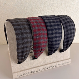 Detailed macro view of four plaid wide headbands in grey, burgundy, and navy woven fabric