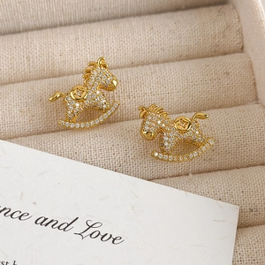 Macro shot of gold rocking horse stud earrings with sparkling cubic zirconia inlay detail