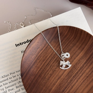 Silver rocking horse necklace with hammered pendant on retro book background