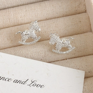 Detailed view of silver rocking horse earrings with sparkling cubic zirconia on velvet