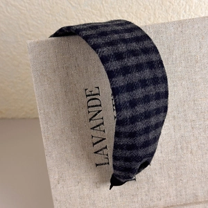 Detailed texture of wide plaid headband with grey and black striped wool fabric