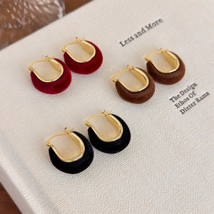 Close-up of three pairs of velvet U-shaped earrings in red, brown and black colors