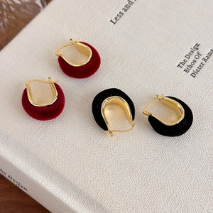 Close-up of red and black velvet U-shaped hoop earrings with gold-toned metal finish