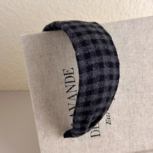 Detail of wide plaid headband in grey and black check pattern with thick fabric texture