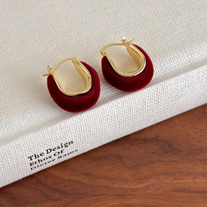 Detailed close-up of burgundy flocked U-shape hoop earrings on a vintage book