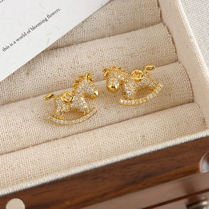 Macro shot of gold rocking horse coin earrings with micro-paved cubic zirconia