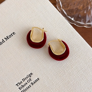 Close-up of vintage red flocked U-shaped earrings on a white textured book background