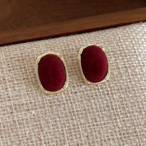 Detail of vintage oval stud earrings with burgundy velvet center and gold wavy metal frame