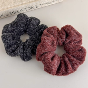 Close-up of dark grey and rust red plush scrunchies with thick wool texture for autumn