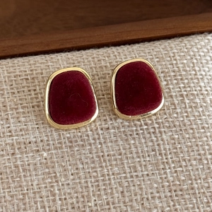Close-up of vintage square velvet stud earrings with burgundy flocking and gold metal frame