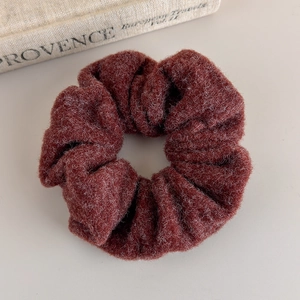 Detail view of burgundy plush woolen scrunchie on vintage book background