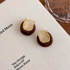Detail shot of vintage gold U-shaped earrings with rich dark brown velvet texture