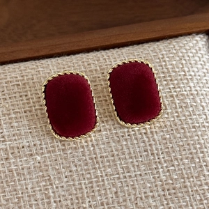 Close-up of vintage burgundy velvet square earrings with detailed gold twisted metal edges