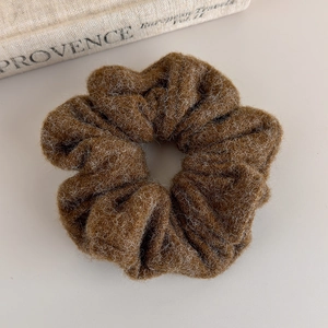 Detailed close-up of a caramel brown wool-like fabric scrunchie with warm soft texture