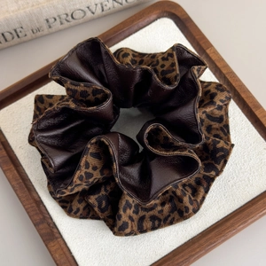 Chouchou double couche en tissu léopard et similicuir marron sur un plateau en bois