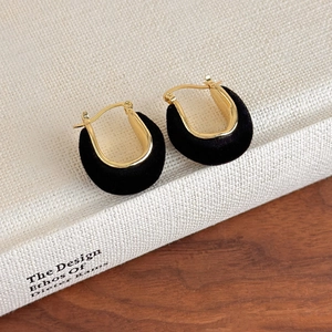 Detail shot of vintage U-shaped gold earrings with black velvet coating on a book