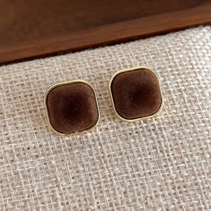 Detail of square vintage brown velvet stud earrings with elegant gold metal edging
