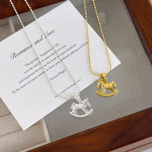 Fashionable rocking horse pendant necklace in gold and silver with hammer-texture detail