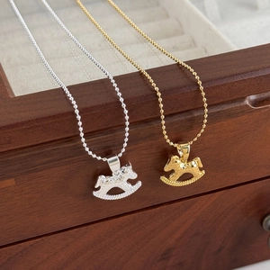 Detailed close-up of gold and silver rocking horse pendants on bead chains