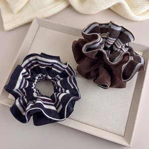 Elegant oversized knit and velvet scrunchies in brown and navy on a textured tray