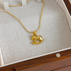 Detail of golden rocking horse pendant with hammer texture on bead chain for women