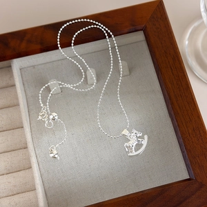 Detail shot of silver rocking horse pendant necklace on beige jewelry box lining
